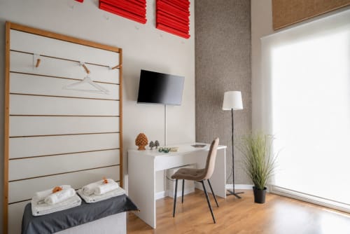 Modern hotel room at I Colori della Sicilia in Caltagirone with desk, TV, comfortable chair, and garden view through bright