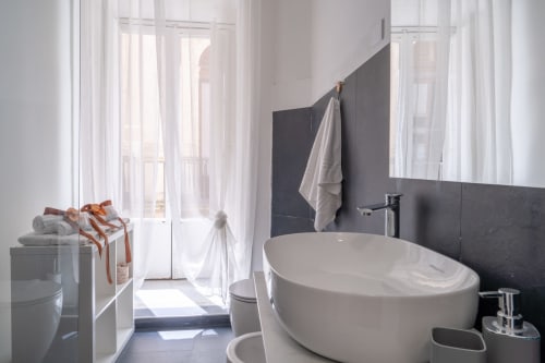 Modern bathroom with oval bathtub, dark tile accents, and garden views at I Colori della Sicilia, Caltagirone, Sicily