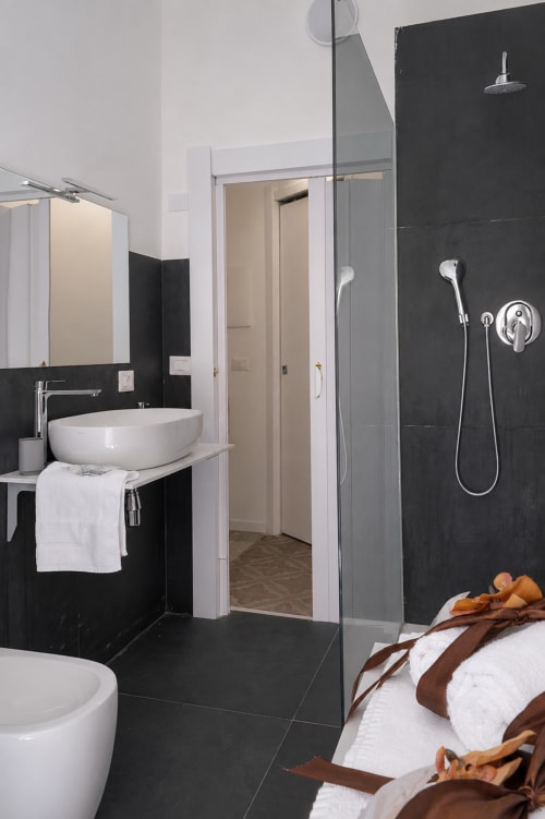 Modern bathroom in Ambra room at I colori della Sicilia B&B, Caltagirone, with black tiles, rainfall shower, vessel sink, and
