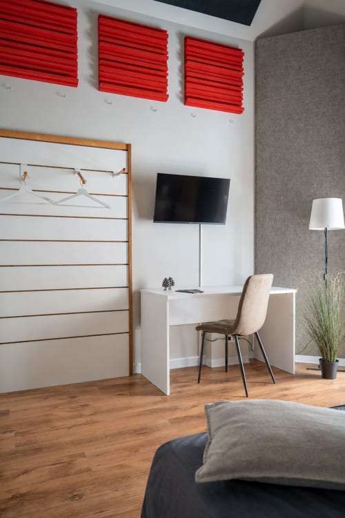 Modern bedroom at I colori della Sicilia in Caltagirone with red acoustic panels, white desk, TV, and wooden flooring