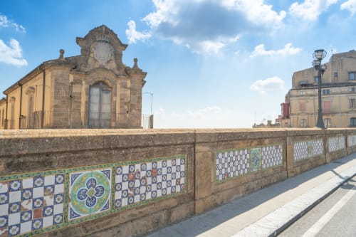 Le iconiche piastrelle ceramiche di Caltagirone e i storici edifici in pietra sotto il cielo blu a I colori della Sicilia