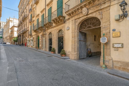 Affascinante strada in ciottoli a Caltagirone, Sicilia con edifici in pietra gialla e persiane verdi vicino a I colori