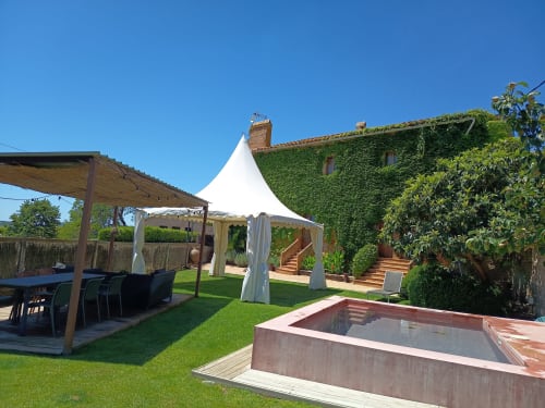 Piscina privada y jardín en Apartmentos Rectoria de Regencós en Costa Brava con tienda blanca, terraza de madera y piedra cubierta de hiedra
