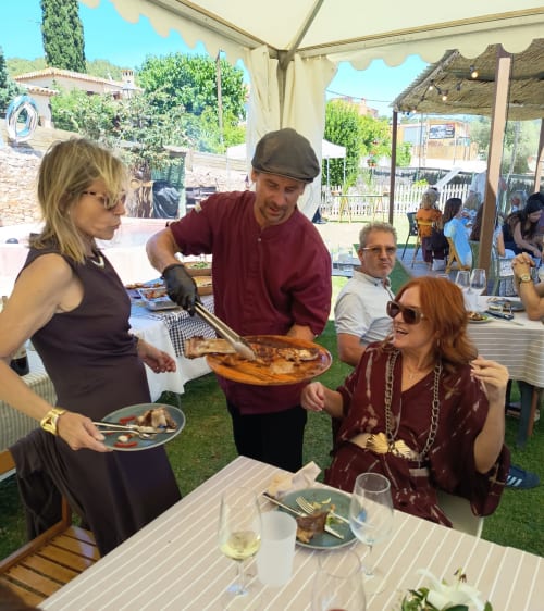 Le serveur présente du poisson grillé aux clients lors d'un dîner en jarddin en plein air, Apartmentos Rectoria Costa Brava