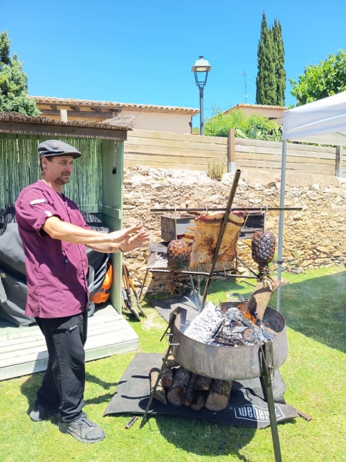 Homme démontrant l'installation d'un barbecue extérieur au cottage de location Costa Brava avec vue sur le jardin et équipements de cuisson