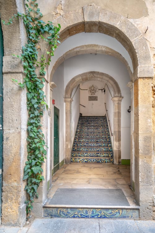 Scalinata ornamentale con piastrelle blu e oro nel palazzo storico di Caltagirone, arcata d'ingresso ricoperta d'edera, La Tegola