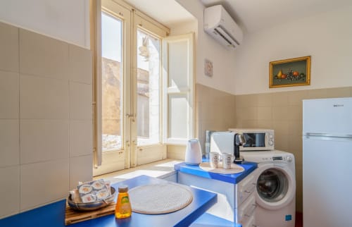 Cucina moderna con piani di lavoro blu, elettrodomestici bianchi e luce naturale nell'appartamento La Tegola di I colori della