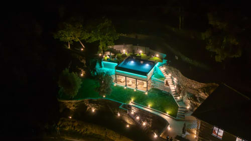 Vista aérea noturna do Douro Sky Valley com piscina iluminada, terraço e iluminação paisagística verde