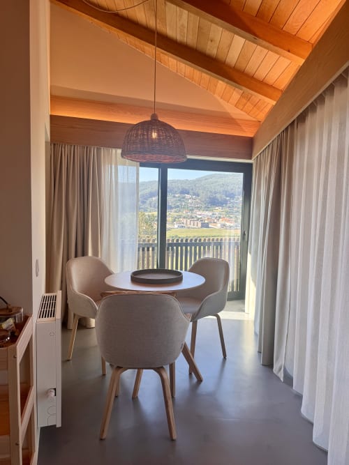 Modern dining area at Quinta Das Pirâmides villa with mountain views, round table, pendant light, and terrace overlooking