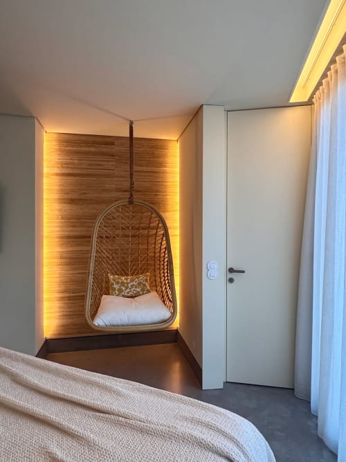 Modern hotel room nook with hanging woven egg chair, warm ambient lighting, white wardrobe, and cream bedding at Quinta Das