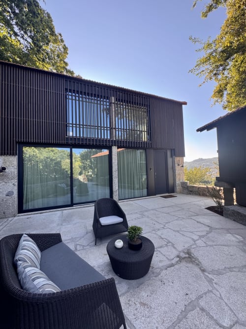 Modern villa patio at Quinta Das Pirâmides with black wicker seating, mountain views, and contemporary architecture in Vila