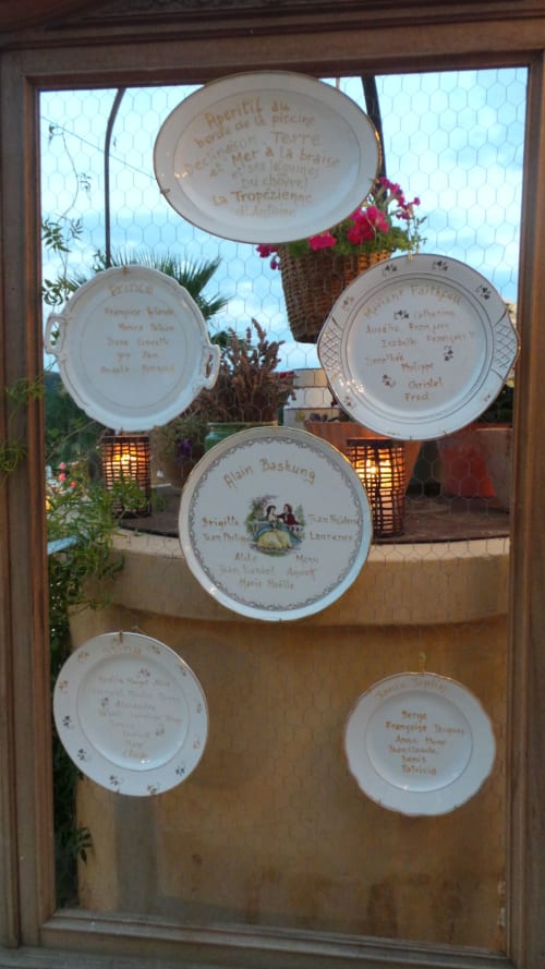 Assiettes décoratives exposées à la fenêtre du gîte Clos Bb à Saint-Cyr sur Mer, avec noms d'hôtes et menu français