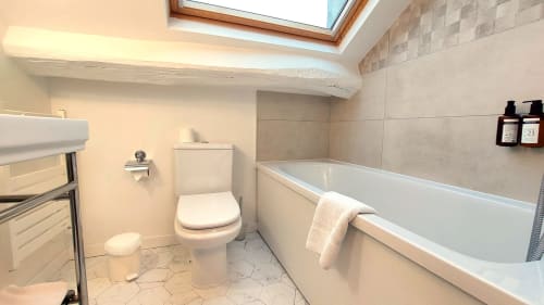 Salle de bain moderne de l'Hôtel Dandy Rouen avec baignoire, toilettes et fenêtre de toit