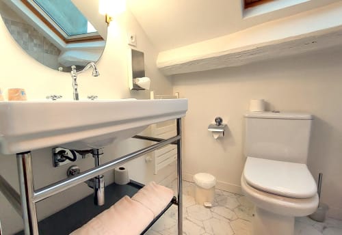 Salle de bain moderne de l'Hôtel Dandy Rouen avec lavabo blanc, toilettes, puits de lumière et revêtement en marbre