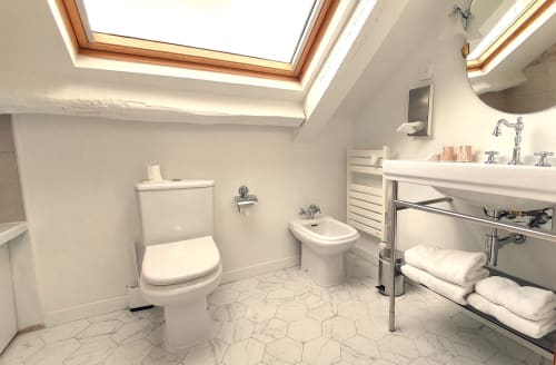 Salle de bain mansardée lumineuse à l'Hôtel Dandy Rouen avec puits de lumière, équipements blancs, lavabo sur pied et sèche-serviettes électrique