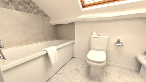 Salle de bain moderne avec baignoire, toilettes et carrelage blanc hexagonal à l'Hôtel Dandy à Rouen