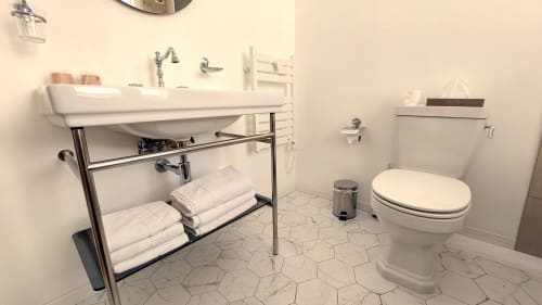Salle de bain moderne de l'Hôtel Dandy Rouen avec lavabo blanc, toilettes, carrelage hexagonal en marbre et serviettes empilées