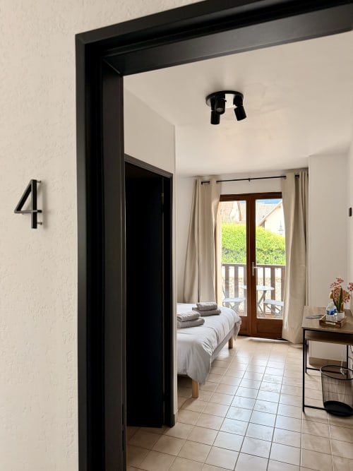 Chambre double de l'Hôtel le Tilleul avec balcon à Corps, France - lit visible à travers la porte