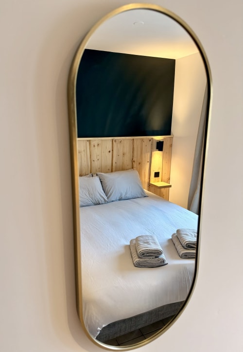 Reflet du miroir de la chambre à l'Hôtel le tilleul, Corps, montrant un lit double avec serviettes et tête de lit en bois