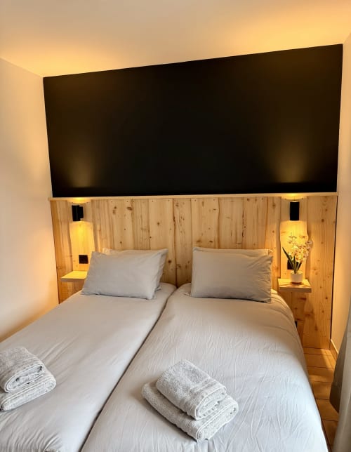 Chambre twin à l'Hôtel le tilleul à Corps avec tête de lit en bois, literie blanche, éclairage ambiant et vue sur les montagnes