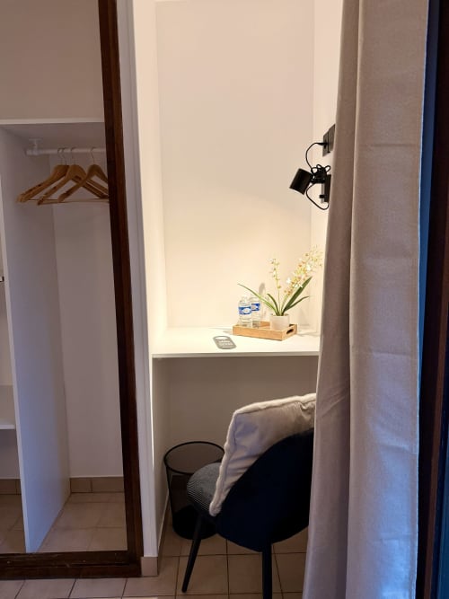 Chambre de l'Hôtel le Tilleul avec bureau, chaise, armoire et fleurs en pot à Corps, France