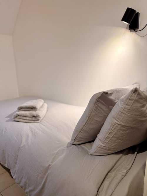 Chambre minimaliste à l'Hôtel le tilleul avec lit, oreillers, serviettes et applique murale à Corps, France