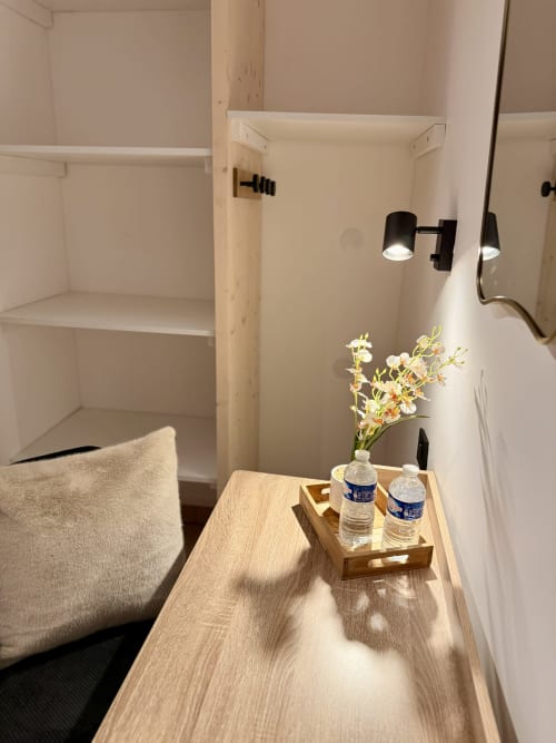Détail de chambre Hôtel le tilleul : bureau en bois avec fleurs, bouteilles d'eau et applique murale
