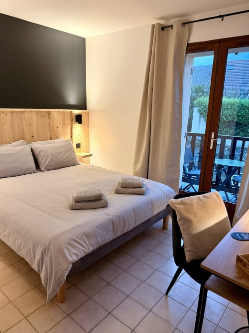 Chambre double moderne à l'Hôtel le tilleul à Corps avec tête de lit en bois, literie blanche, portes-fenêtres et vue sur la montagne