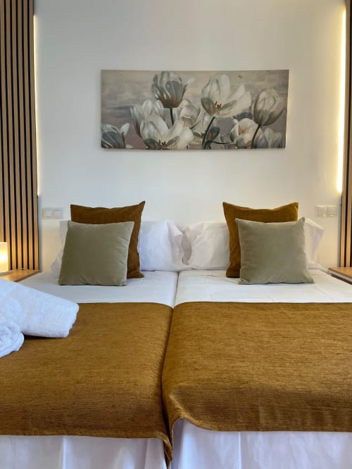 Dormitorio moderno del Hotel Arenas Rio en Arenas de San Pedro con camas gemelas, detalles dorados y obra de arte floral