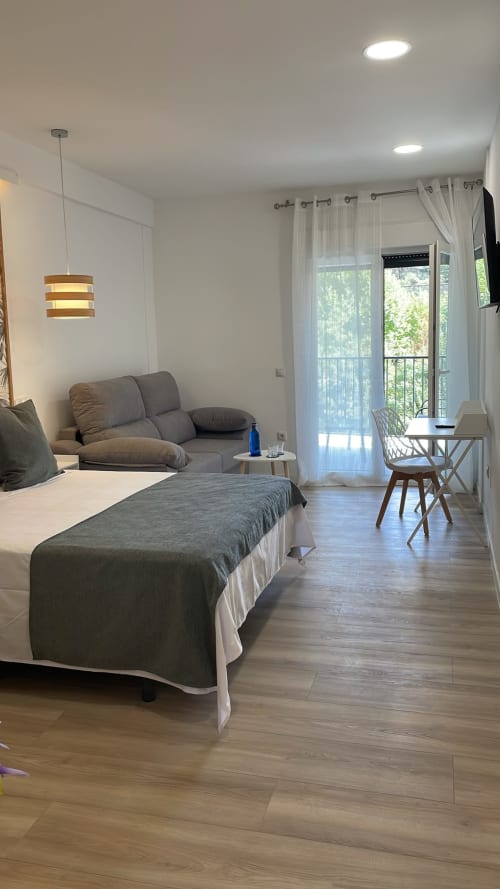 Habitación moderna del Hotel Arenas Rio en Arenas de San Pedro con cama, sala de estar y vista al balcón