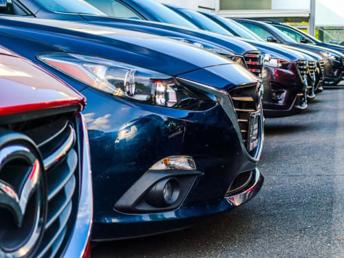 Fila de coches de alquiler azules estacionados en el Hotel Arenas Rio de Arenas de San Pedro, España