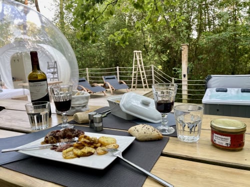Salle à manger en plein air aux Bulles De Bordeaux avec vin, cuisine gastronomique et vue sur la forêt à Salleboeuf