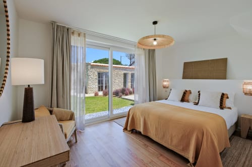 Bright bedroom at Sea'Ya Villa Juso with king bed, mountain views through glass doors, wooden pendant light, and access to