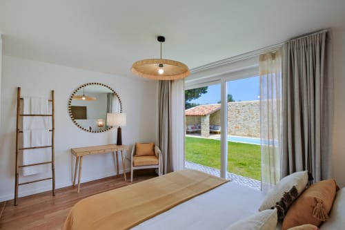 Luxury villa bedroom with wooden desk, round mirror, mountain views, and private garden access at Sea'Ya Villas, Aldeia de