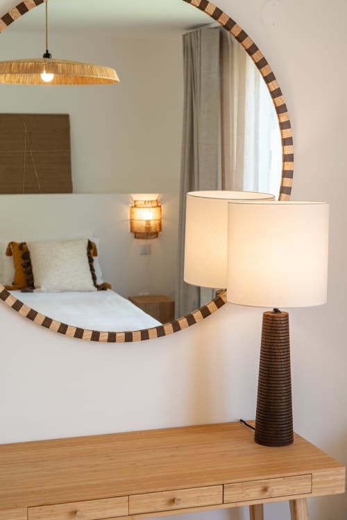 Stylish bedroom at Sea'Ya Villa Juso with round wooden-framed mirror, wooden desk lamp, and pendant light