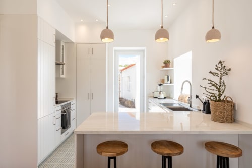 Modern kitchen with white cabinetry, pendant lights, and wooden bar stools at Sea'Ya Villa Juso in Portugal