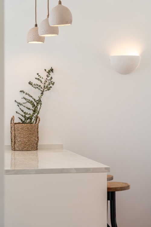 Minimalist villa interior with pendant lights, white counter, woven plant pot, and wall sconce at Sea'Ya Villas