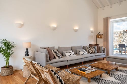 Modern living room at Sea'Ya Villa Juso with gray sofa, wooden table, woven chairs, and mountain views through terrace doors