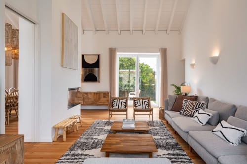 Modern villa living room at Sea'Ya Villas with gray sofa, wooden furniture, geometric artwork, and mountain views through