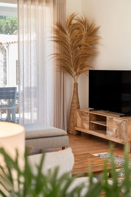 Bright living room at Sea'Ya Villa Juso with wooden TV stand, tall pampas grass décor, beige furniture, and mountain views