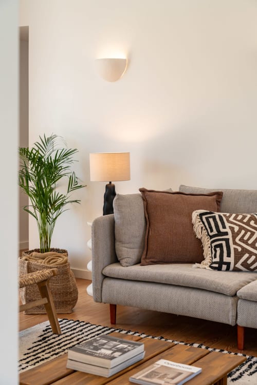 Cozy villa living room with beige sofa, decorative pillows, table lamp, potted plant, and wooden floors at Sea'Ya Villas