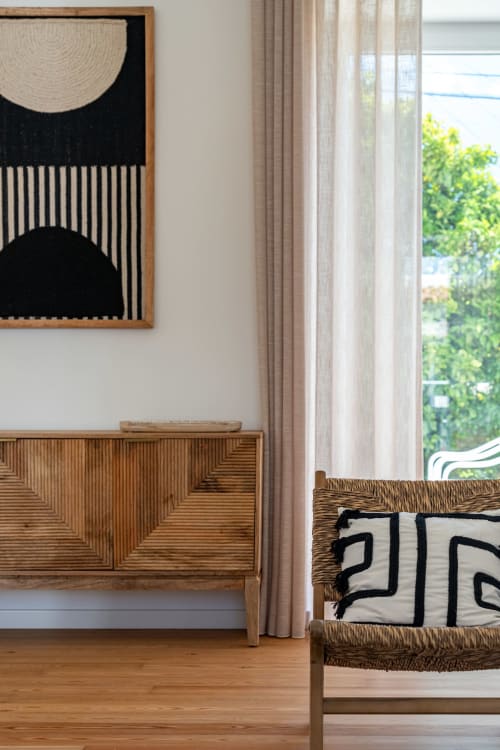 Modern villa interior with geometric wall art, wooden sideboard, and woven chair at Sea'Ya Villas, Portugal