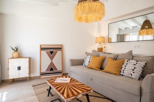 Modern villa living room at Sea'Ya Villas with gray sofa, golden pillows, geometric artwork, and woven pendant lights