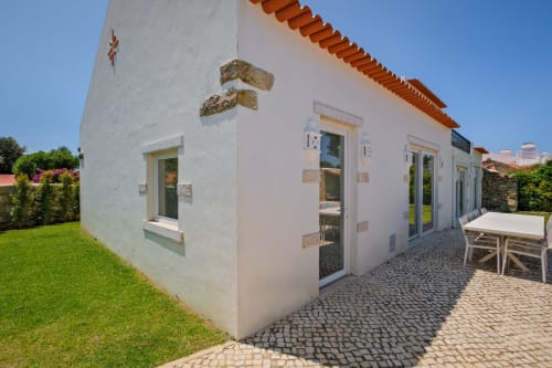 Sea'Ya Villa Juso in Aldeia de Juso features white exterior with terracotta roof, patio seating, and manicured garden
