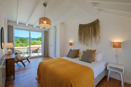 Modern villa bedroom at Sea'Ya Villas with mountain views, queen bed, woven wall art, balcony access, and contemporary