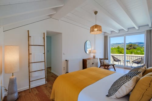Bright modern bedroom at Sea'Ya Villas with mountain views, yellow bedding, wooden ladder decor, and private balcony