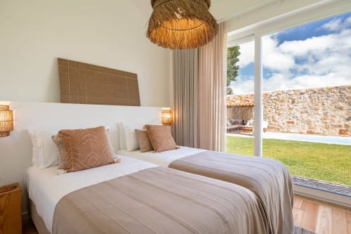 Bright bedroom at Sea'Ya Villa Juso with twin beds, mountain views through glass doors, and woven pendant lamp