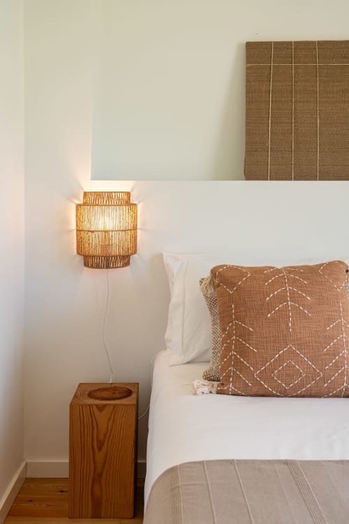 Cozy bedroom corner at Sea'Ya Villa Juso with woven pendant lamp, wooden nightstand, and brown patterned pillow on white