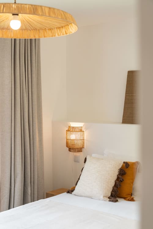 Cozy bedroom corner at Sea'Ya Villas with woven pendant light, cream pillows, and beige curtains