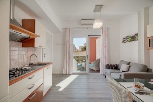 Modern open-plan kitchen and living area at Short Let's Olbia with wood accents, gas stove, and sea view balcony